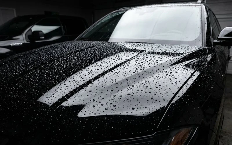 Dark SUV with ceramic coating showing water beading on the hood after rain in an Idaho driveway